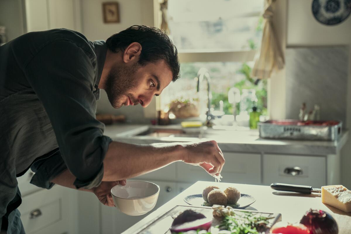 A chef sprinkles cheese on food in his kitchen