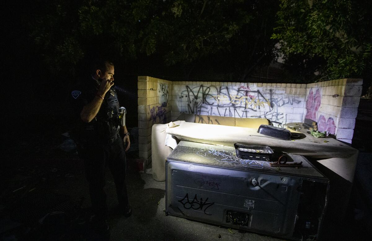 A police officer looks for homeless people during the Point in Time homeless count.