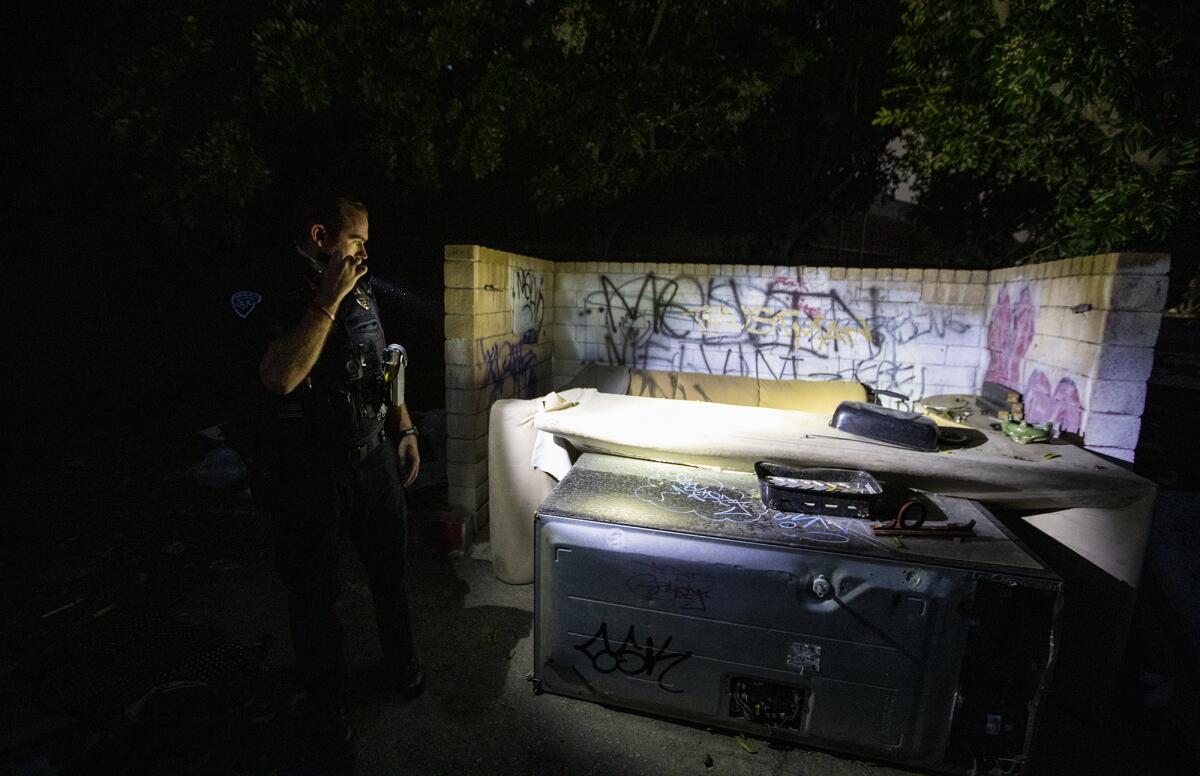 Officer Adam Hunter with the Westminster Police Department looks for homeless people in Fountain Valley.