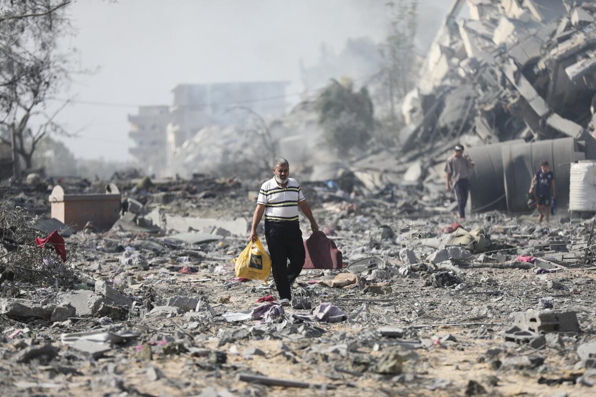 ARCHIVO - Algunos palestinos caminan junto a edificios destruidos tras un bombardeo israelí