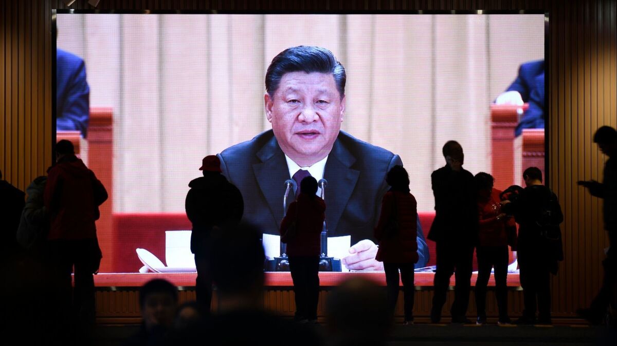 People walk past a screen showing video footage of Chinese President Xi Jinping at an exhibition at the National Museum of China in Beijing on Feb. 27.