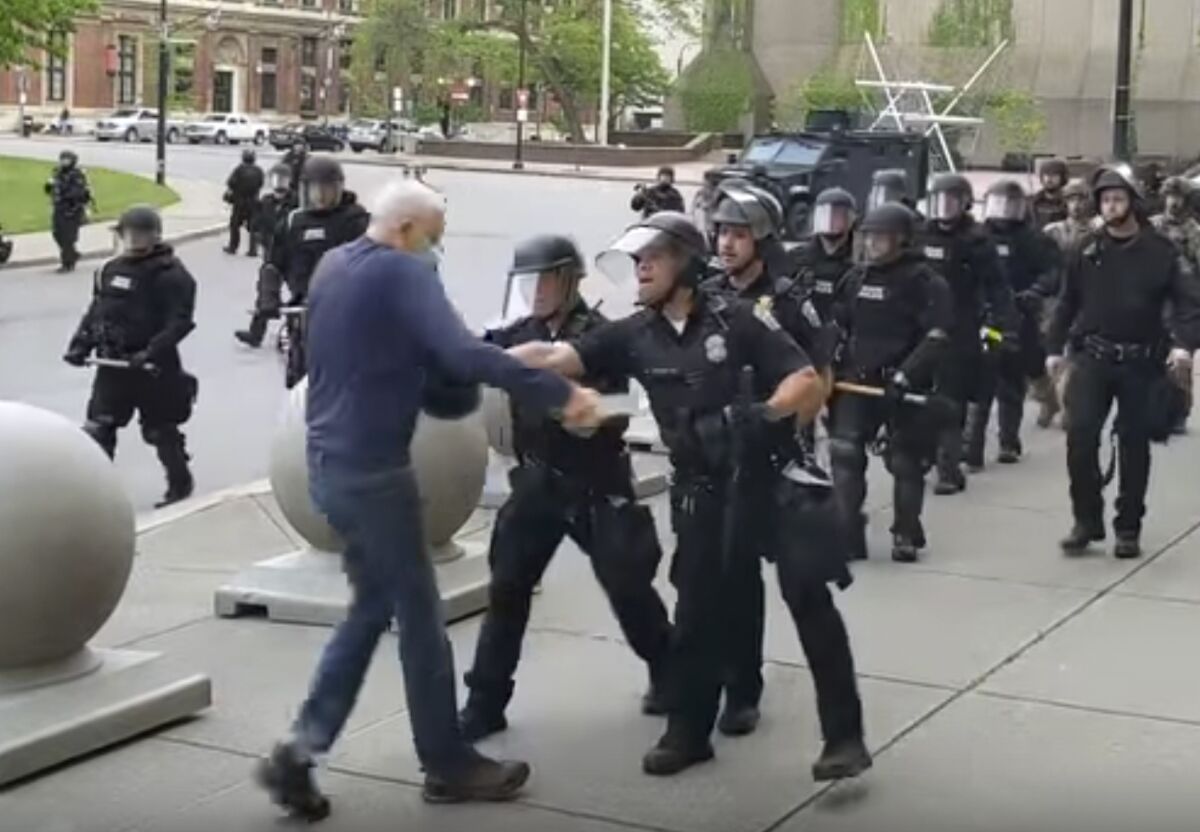 In this image from video provided by WBFO, a Buffalo police officer appears to shove a man who walked up to police Thursday, June 4, 2020, in Buffalo, N.Y. Video from WBFO shows the man appearing to hit his head on the pavement, with blood leaking out as officers walk past to clear Niagara Square. Buffalo police initially said in a statement that a person “was injured when he tripped & fell,” WIVB-TV reported, but Capt. Jeff Rinaldo later told the TV station that an internal affairs investigation was opened. Police Commissioner Byron Lockwood suspended two officers late Thursday, the mayor’s statement said. (Mike Desmond/WBFO via AP)