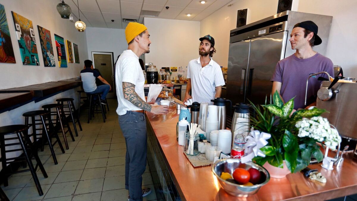 John Schwarz, center, and Jackson Defa, right, serve customers at Weird Wave Coffee.