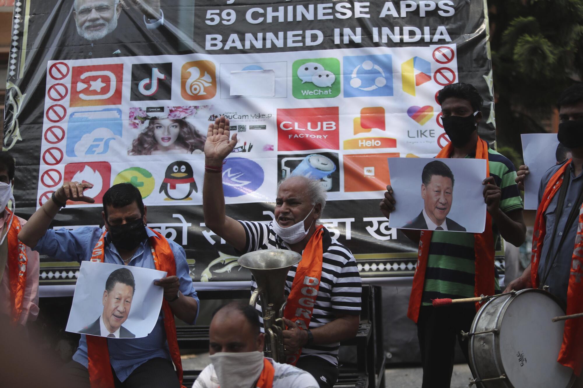 People holding musical instruments and images of a man raise hands in front of a large poster about banned Chinese apps