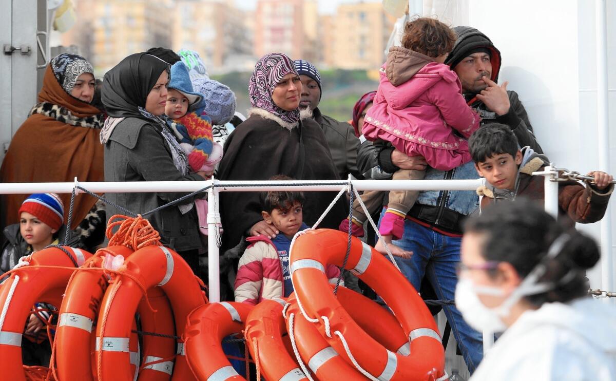 Migrants wait to disembark from an Italian coast guard vessel in Porto Empedocle, Italy, on March 4, 2015. In a dramatic sea rescue north of Libya, a flotilla of ships saved more than 900 migrants, though 10 died, Italian officials said.