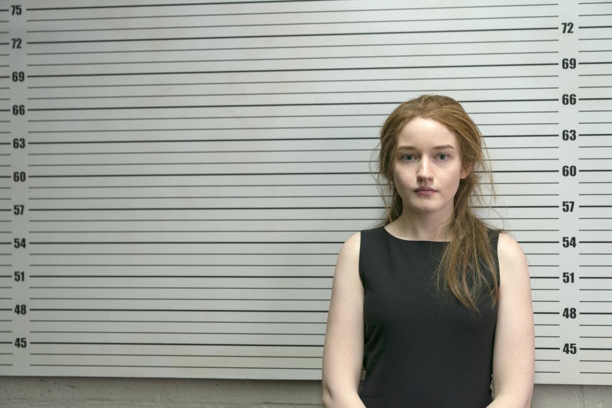 A young woman looks directly into the camera as she has her picture taken at the police station.