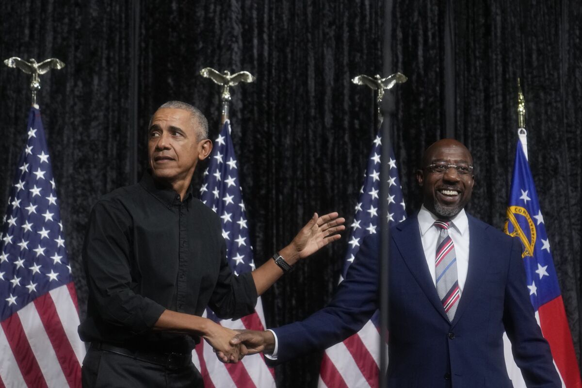 Former President Obama, left, greets Sen. Raphael Warnock.