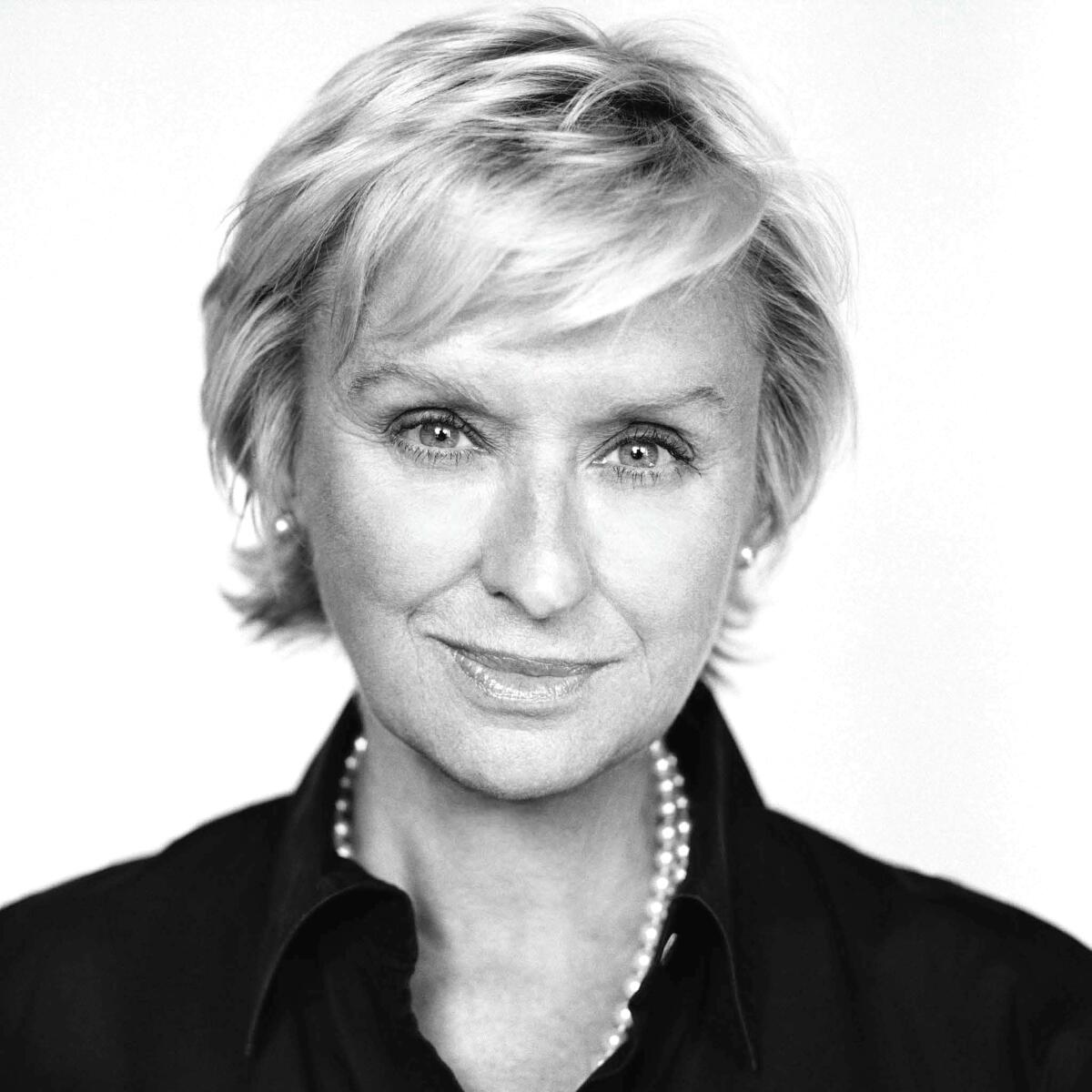 A black-and-white headshot Tina Brown with short hair, wearing pearls.