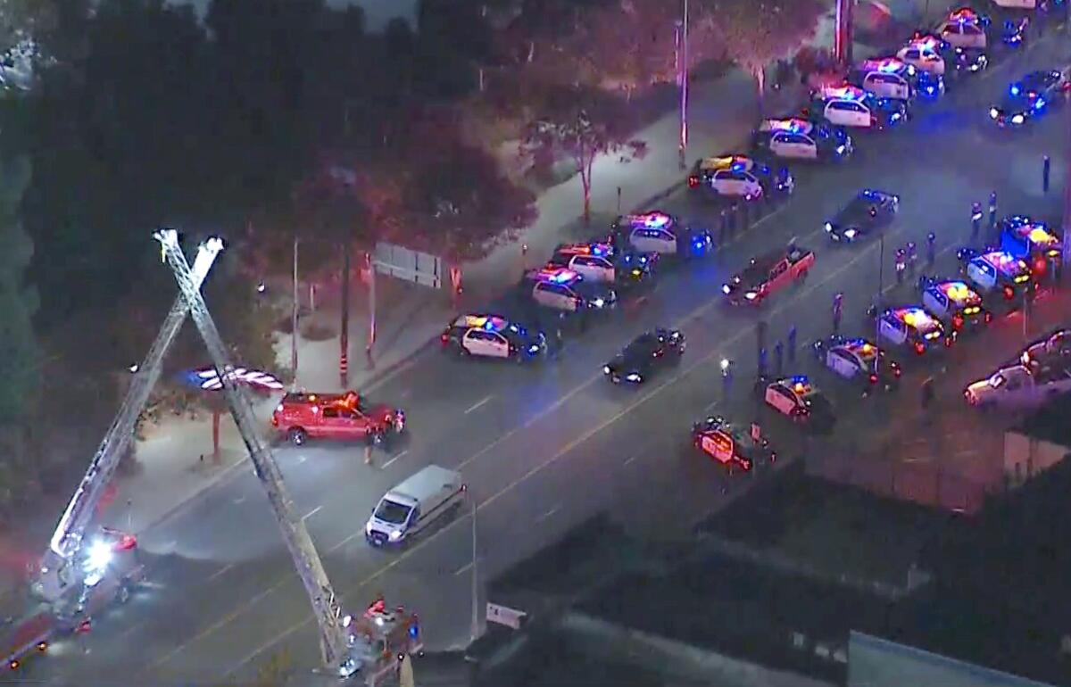 Firetrucks and police cars in a procession for a slain LAPD officer