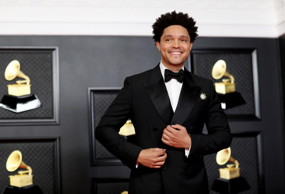 A man in a tuxedo surrounded by photographs of Grammy Awards.