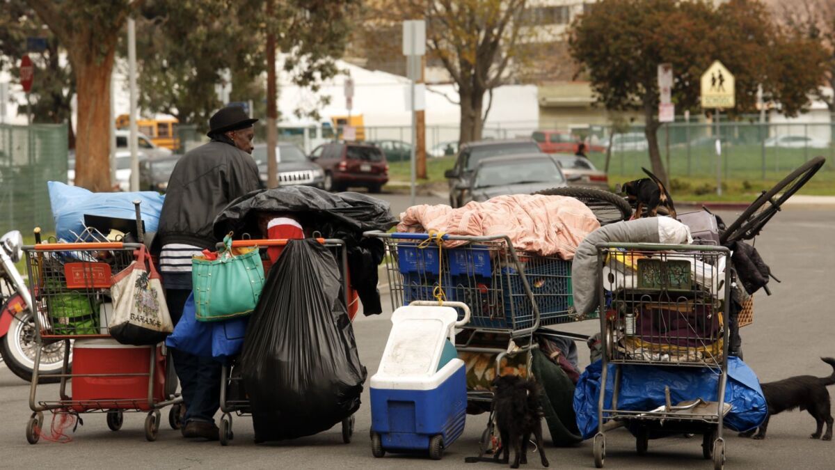 Ricky Riller, 59, carries his belongings and dogs in shopping carts before sanitation workers sweep the homeless encampments in the Manchester Square neighborhood in Los Angeles.