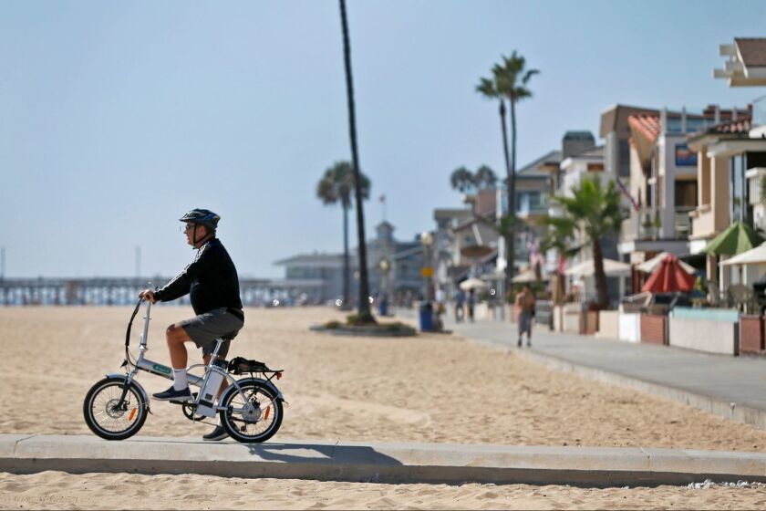 Ken Montgomery, of Irvine, rides his E-Spirit foldable electric bike in Newport Beach on Sept. 21, 2016.