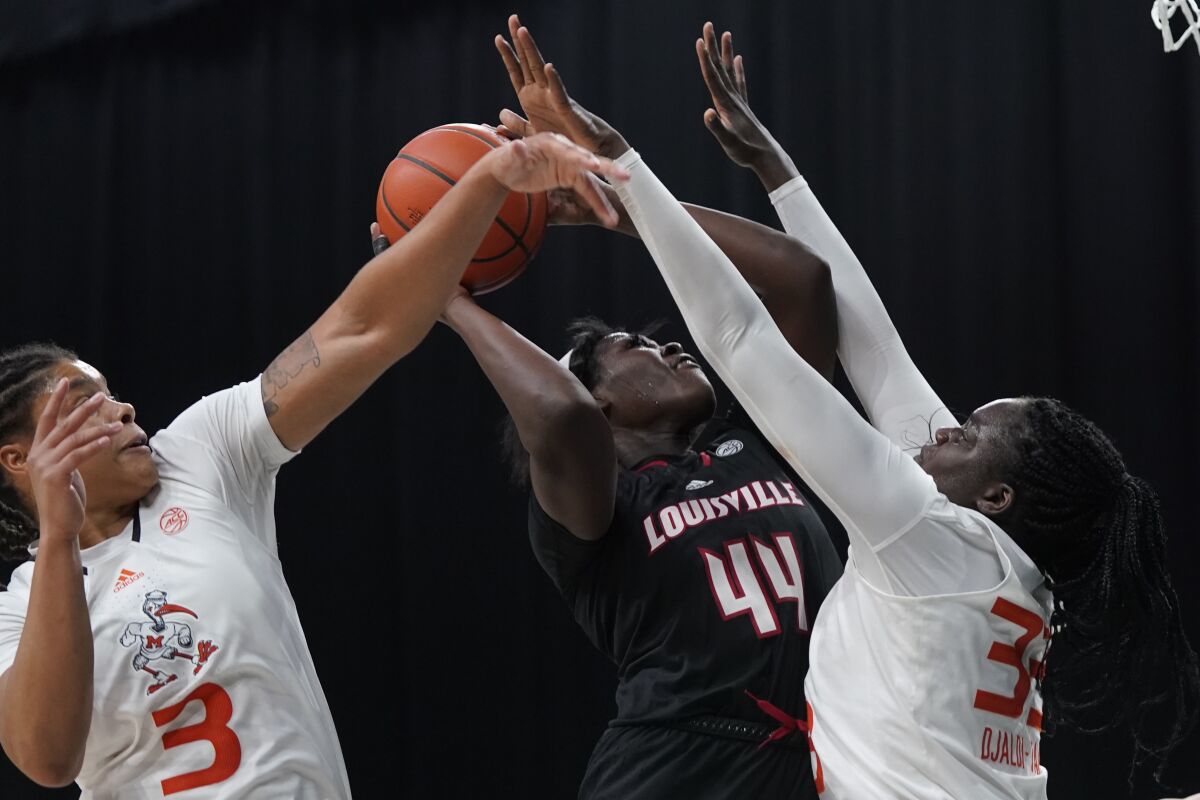Louisville forward Olivia Cochran (44) goes up for a shot against Miami forwards Destiny Harden (3) and Maeva Djaldi-Tabdi (33) during the second half of an NCAA college basketball game, Tuesday, Feb. 1, 2022, in Coral Gables, Fla. (AP Photo/Wilfredo Lee)