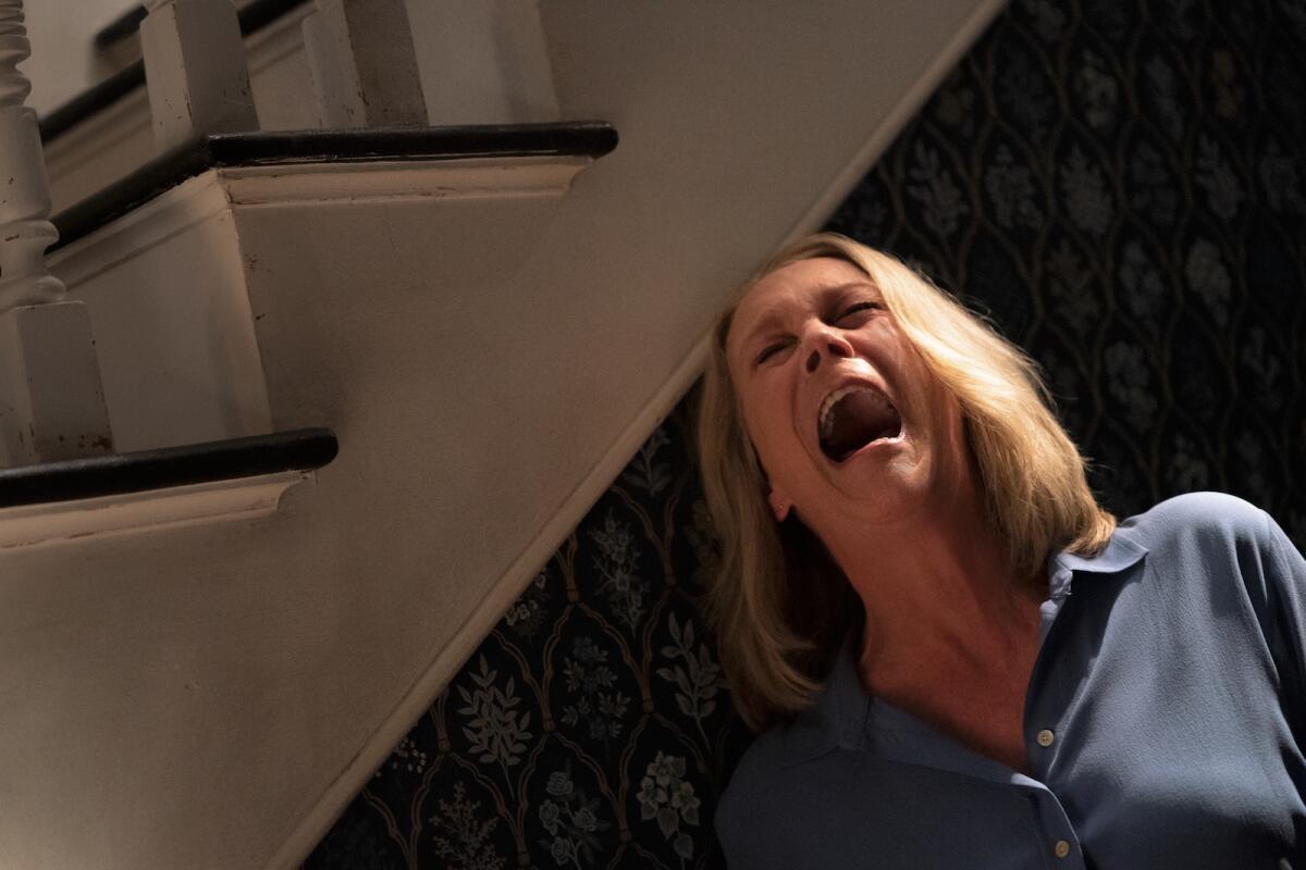 A woman screams beneath a staircase in the movie "Halloween Ends."