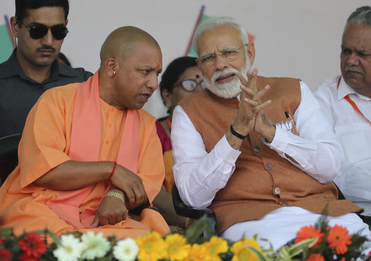 Yogi Adityanath, leader of India's Uttar Pradesh state, speaks with Prime Minister Narendra Modi at a campaign rally.