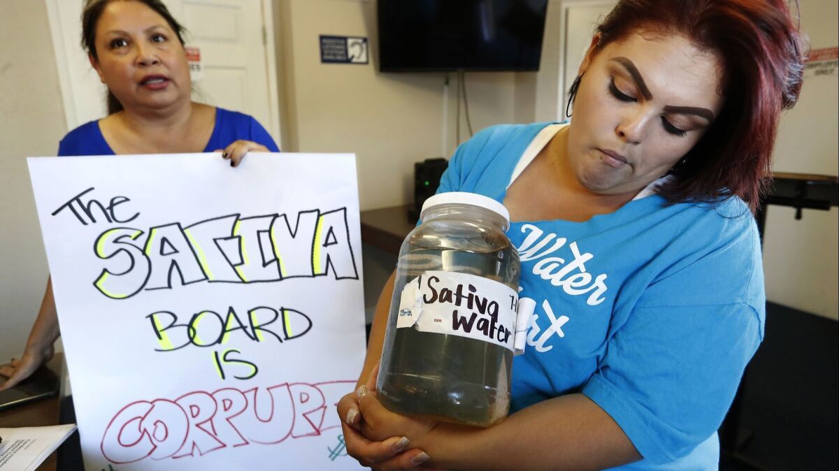 Compton resident Genoveva Camargo, right, holds water from her tap with activist Maria Estrada. They both supported Assembly BIll 1577, which dismantles the Sativa Los Angeles County Water District's board of directors.