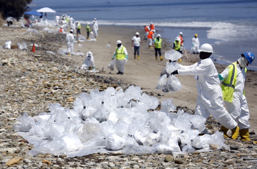 Workers in hazmat suits stack plastic bags on the beach