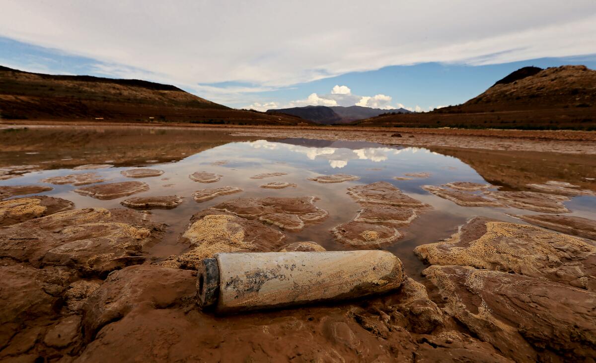  Clouds are reflected on the surface of a pool of water in a drying lakebed.