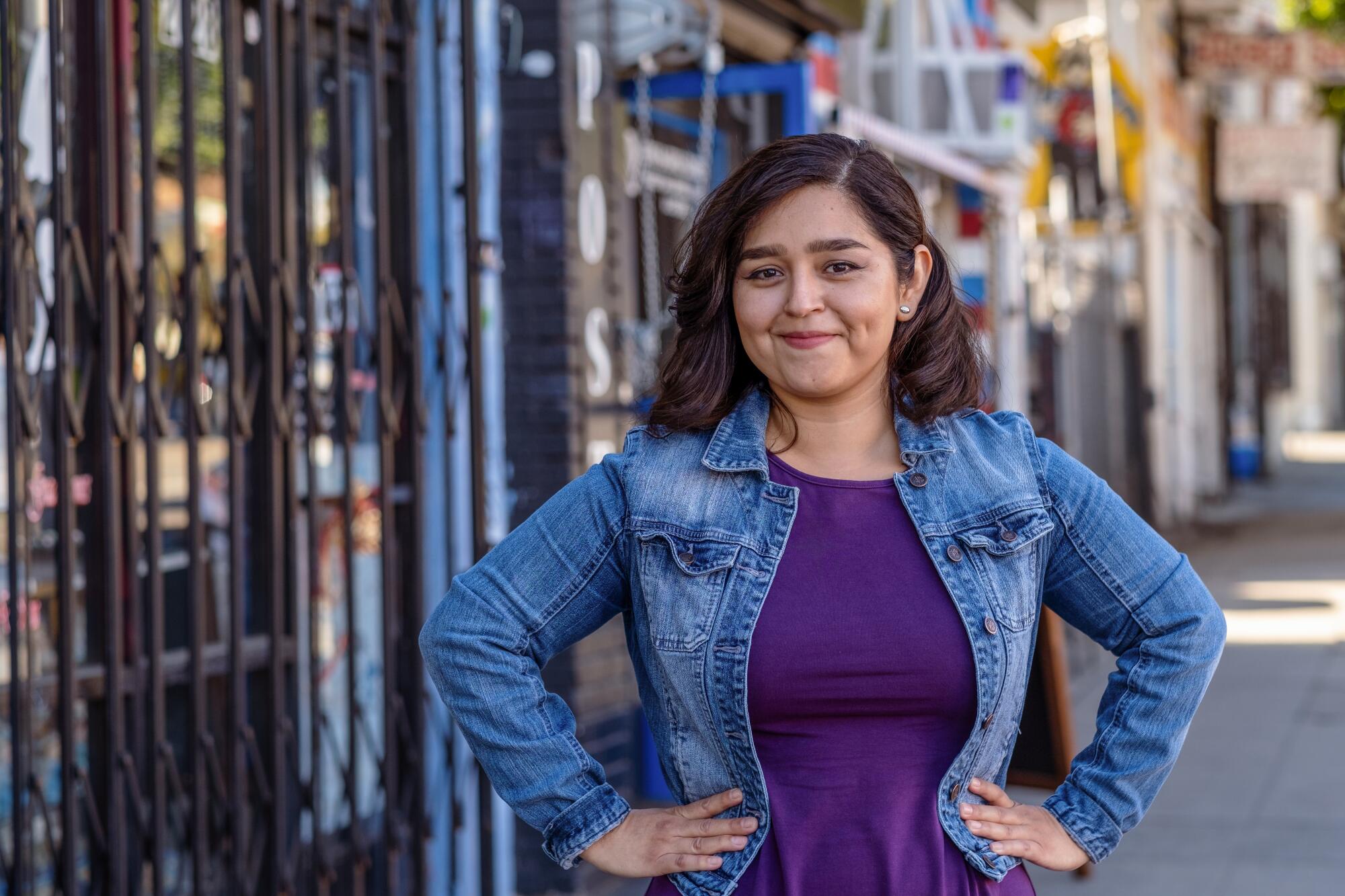 A smiling woman stands, hands on hips, outside a cafe in Boyle Heights. 