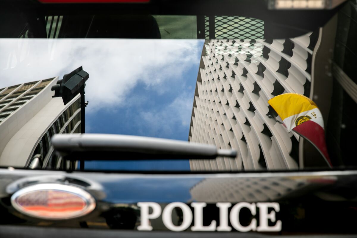 San Diego City Hall is reflected in the rear window of a San Diego Police Department vehicle.