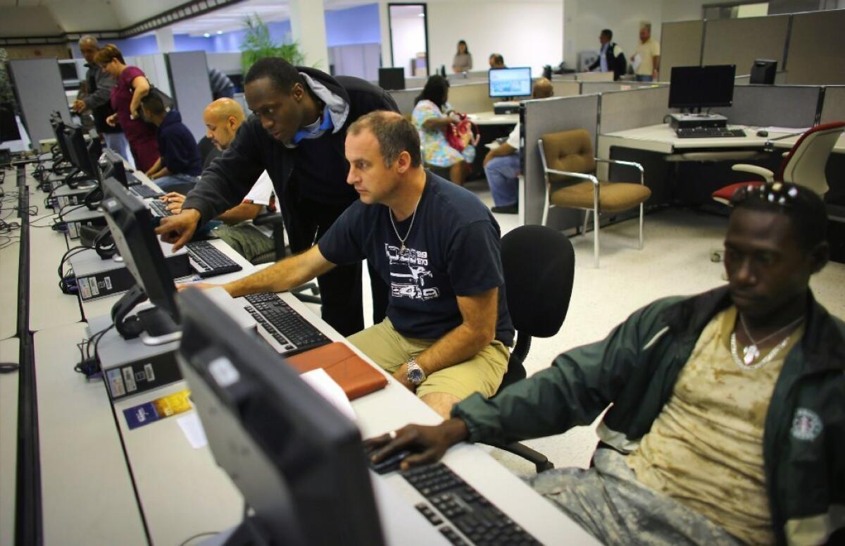 Shane Budde is helped by South Florida Workforce customer service representative Troy Rawlins as he looks for job opportunities on the computer at the South Florida Workforce center in Miami last week.