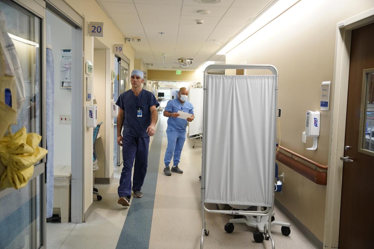 Trabajador de urgencias habla con paciente en una cama en un pasillo del Scripps Memorial Hospital Encinitas
