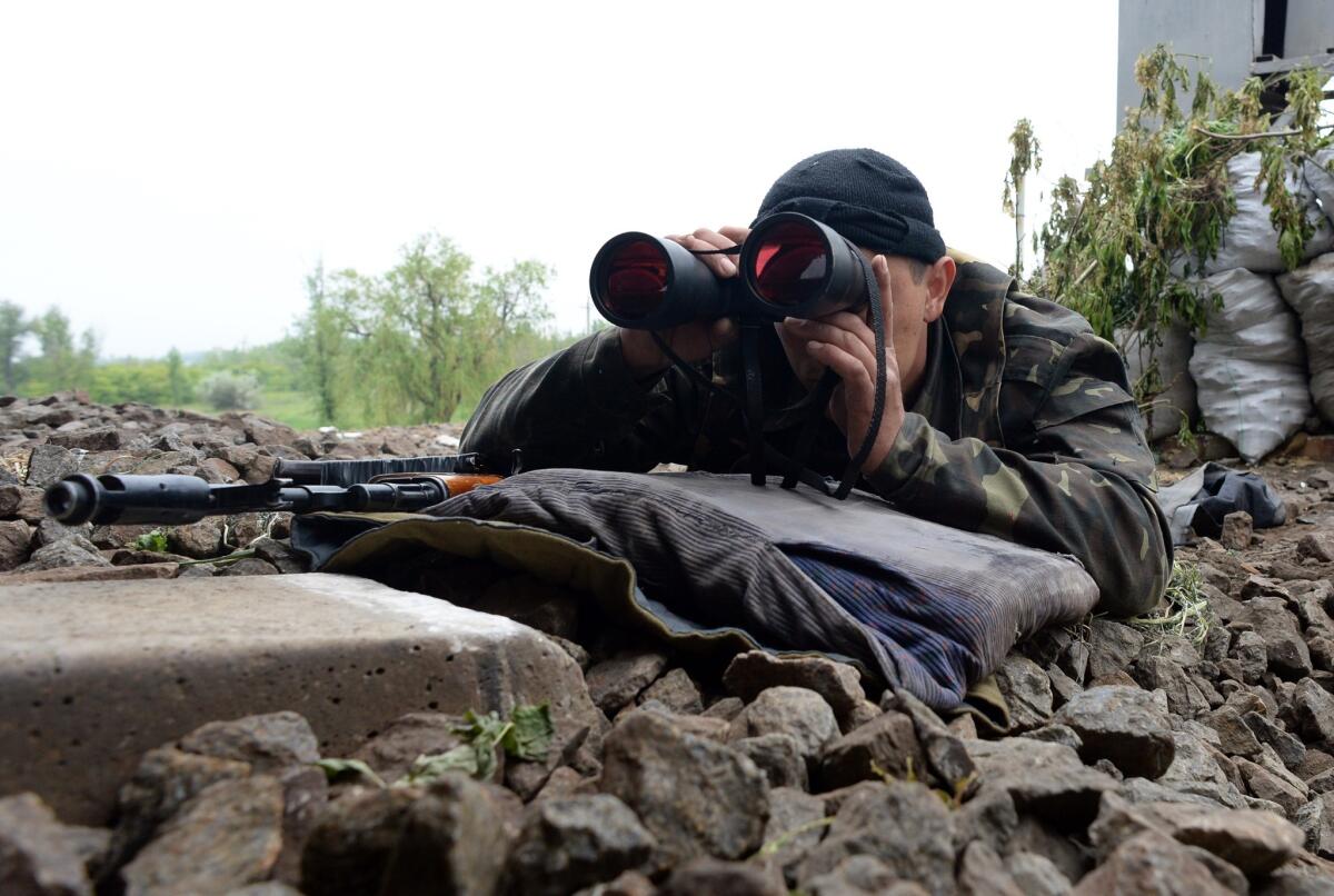An armed pro-Russian fighter takes position Monday at a checkpoint near the eastern Ukrainian city of Slavyansk.