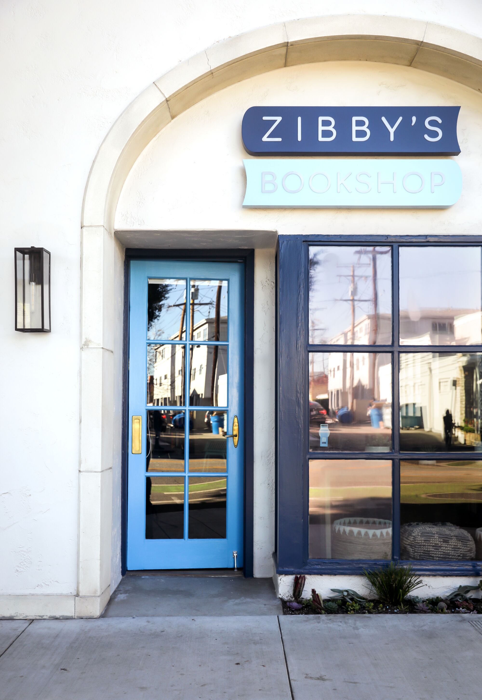 An arched entryway with a blue door and a sign that reads Zibby's Bookshop