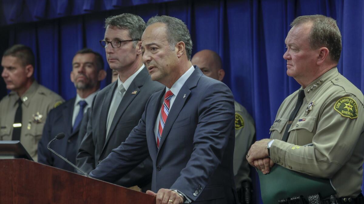 U.S. Attorney Nicola Hanna — with FBI Asst. Director in Charge Paul Delacourt, left, L.A. County Sheriff Jim McDonnell, and other officials — addresses an investigation into the Mexican Mafia in the county jails at a press conference on Wednesday, May 23, 2018.