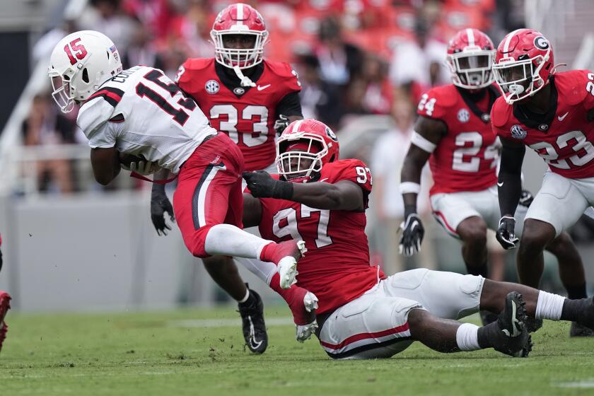 Ball State running back Marquez Cooper (15) escapes from Georgia defensive lineman Warren Brinson (97) in the first half of an NCAA college football game Saturday, Sept. 9, 2023, in Athens, Ga. (AP Photo/John Bazemore)