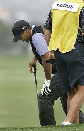 Tiger Woods holds onto his knee as he comes out of a bunker on the fourth hole during the third round of the U.S. Open.