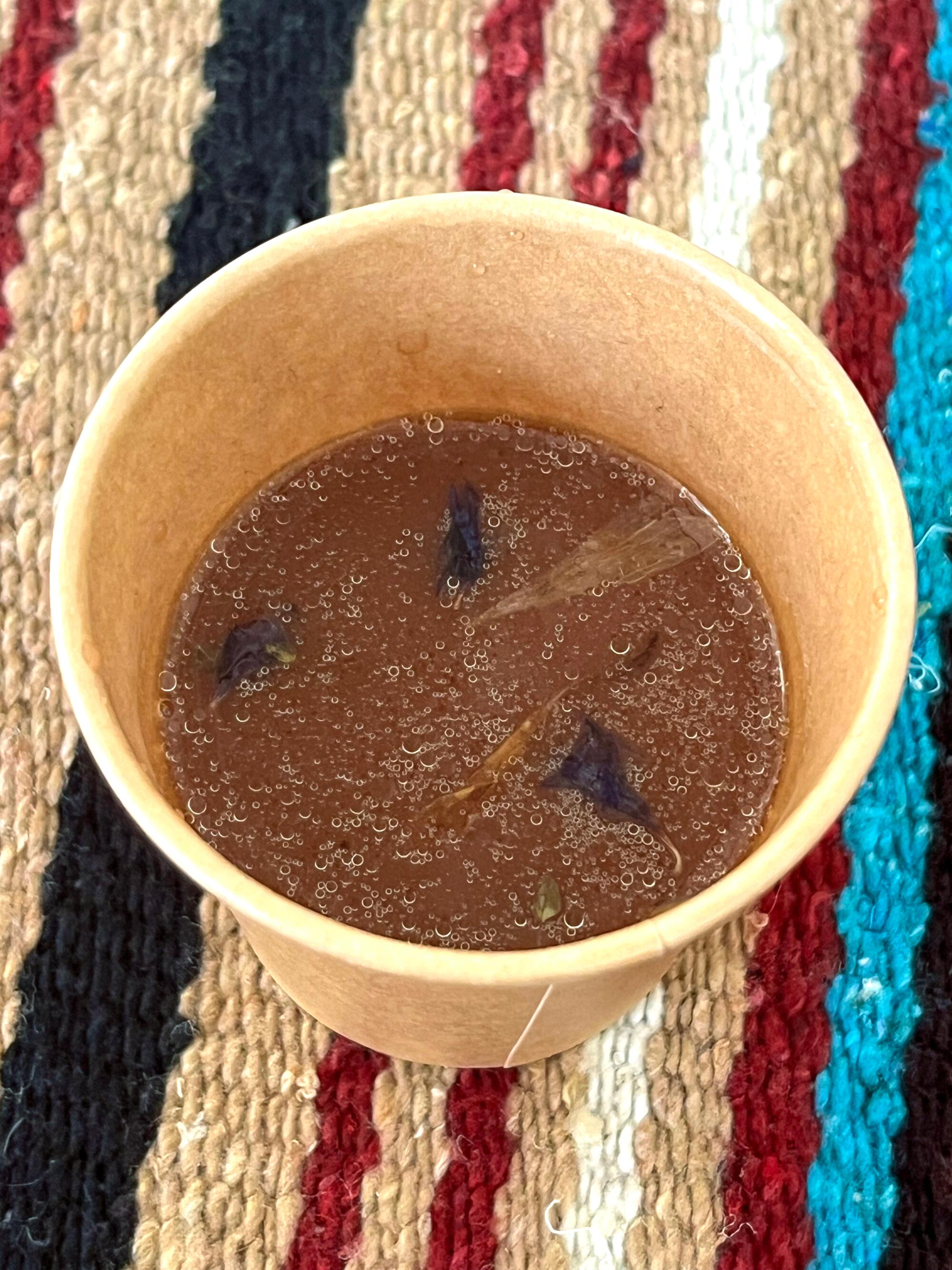 Small edible flowers float on the surface of a cup of cocoa.
