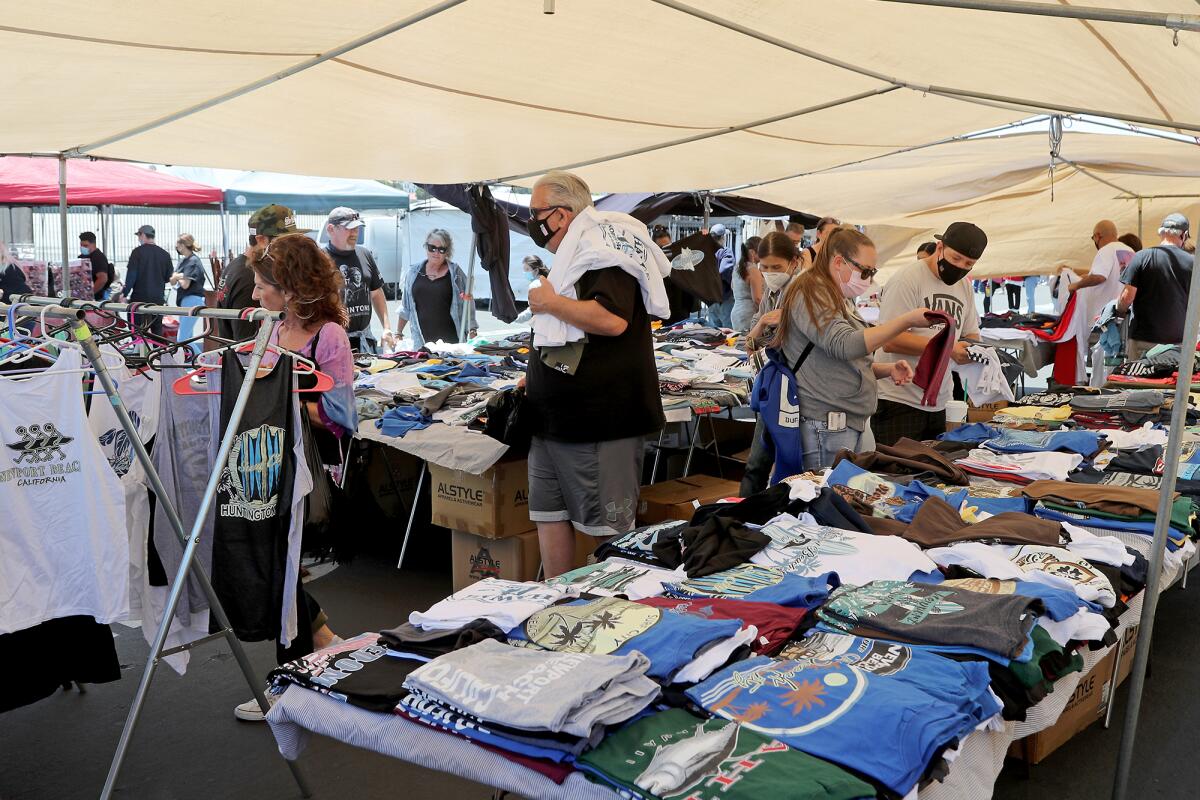 Shoppers search through T-shirts during the O.C. Swap Meet at the fairgrounds in Costa Mesa on Saturday.