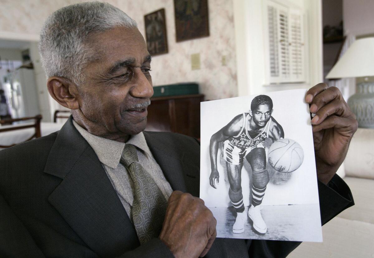 Former Harlem Globetrotter Marques Haynes, in 2008, holds a photo of himself in his team uniform, circa 1951.