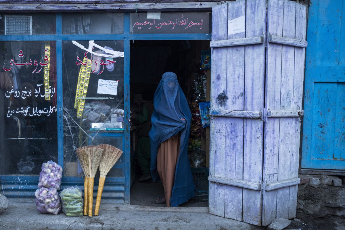 An Afghan woman wearing a burka exits a small shop in Kabul, Afghanistan, Sunday, Dec. 5, 2021. Women's rights activists in the Afghan capital of Kabul insisted Sunday they would continue fighting for their right to education, employment and participation in Afghan political and social life, and said a recent Taliban decree banning forced marriage was not enough to address the issue of women's rights. (AP Photo/Petros Giannakouris)