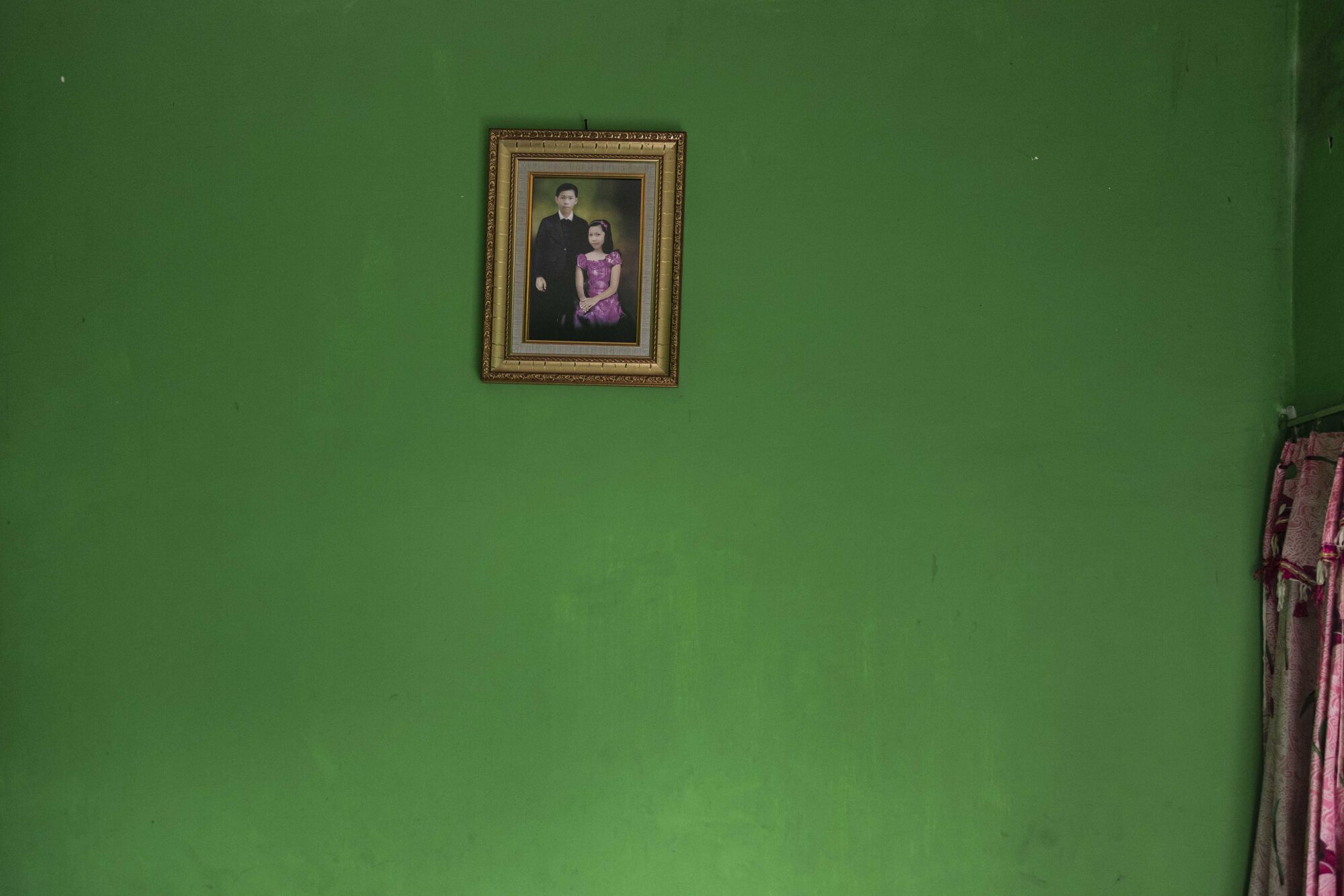 A framed portrait of a girl and boy on a green wall 