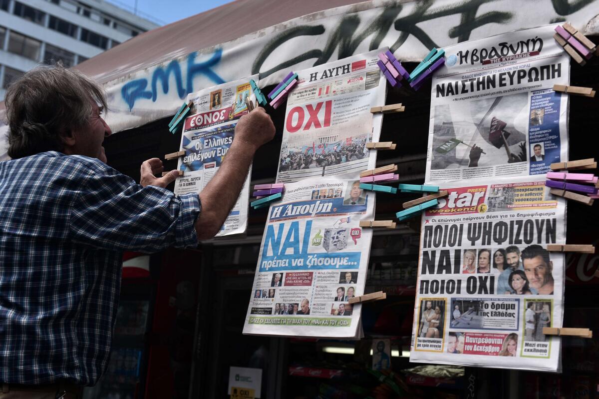 A news agent hangs newpapers bearing "no" and "yes" headlines in central Athens on the eve of the Greek referendum on bailout terms.