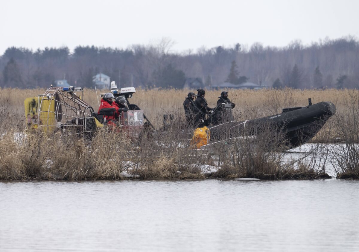 Searchers look for victims in Akwesasne, Quebec, Friday, March 31, 2023. Authorities in the Mohawk Territory of Akwesasne said Friday one child is missing after the bodies of six migrants of Indian and Romanian descent were pulled from a river that straddles the Canada-U.S. border. (Ryan Remiorz/The Canadian Press via AP)