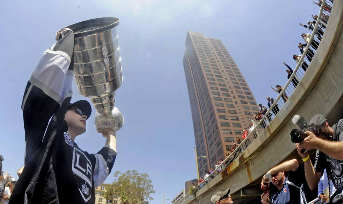 Kings captain Dustin Brown holds the Stanley Cup as fans on an overpass get a wave in downtown Los Angeles.