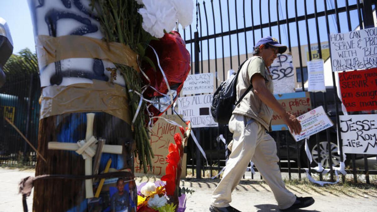 Un hombre pasa frente a cartels, flores y velas colocadas en el area de Boyle Heigts donde Jesse Romero, de 14 anos, murio a manos de agentes del LAPD.