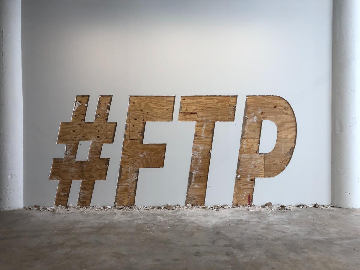 The letters #FTP carved out of gallery drywall by Ruben Ochoa.