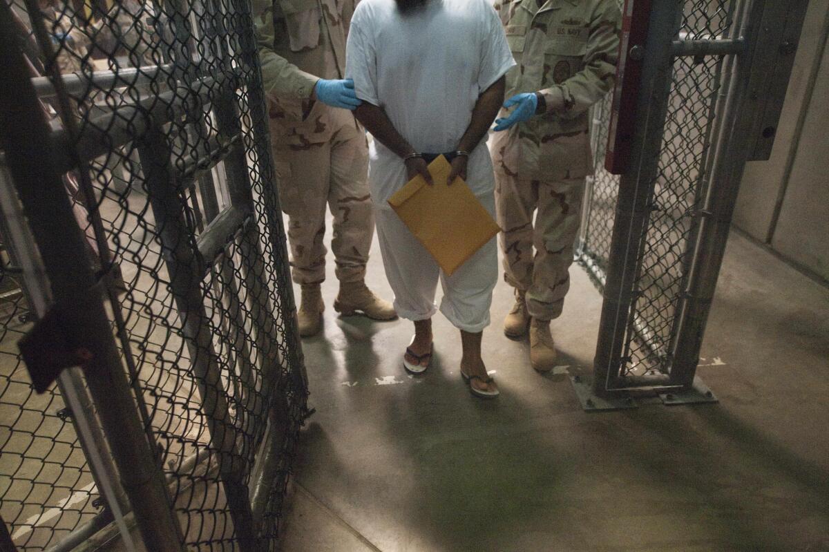 U.S. military guards move a detainee inside the prison camp at Guantanamo Bay, Cuba, in 2010. Six Guantanamo detainees have been transferred to Uruguay from the base, the Pentagon said Dec. 7.