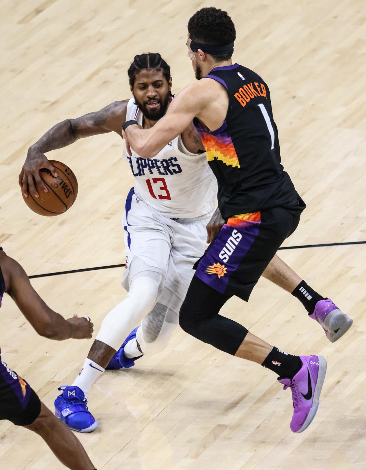 Clippers forward Paul George is closely defended by Suns guard Devin Booker during Game 5.