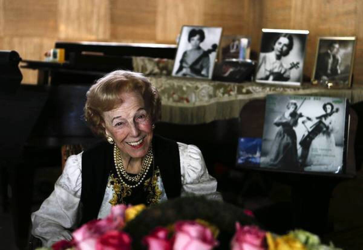 Violinist Alice Schoenfeld, who has taught at USC for more than 50 years, sits near portraits of herself and her late sister, Eleonore Schoenfeld, at her La Cañada Flintridge home.