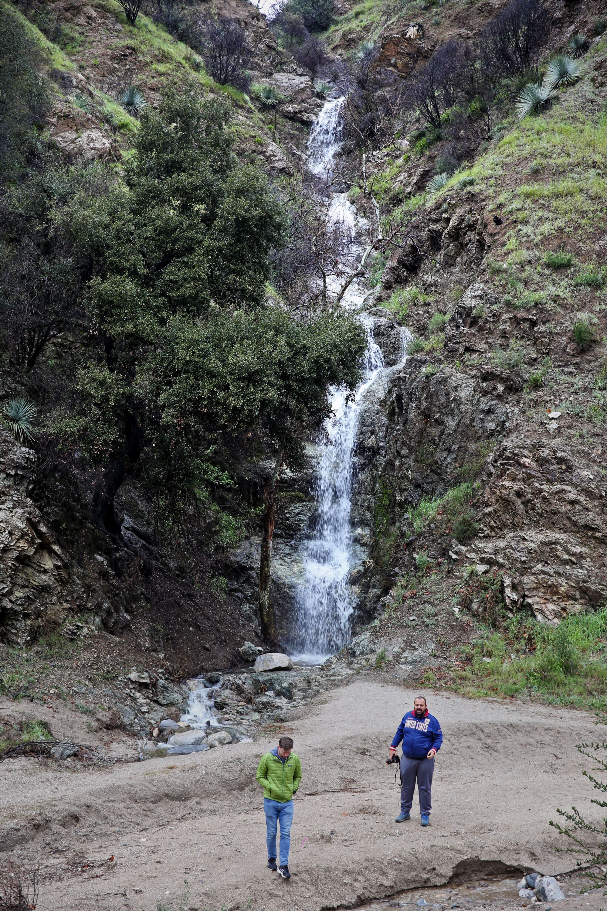 Two people stand near a temporary waterfall 