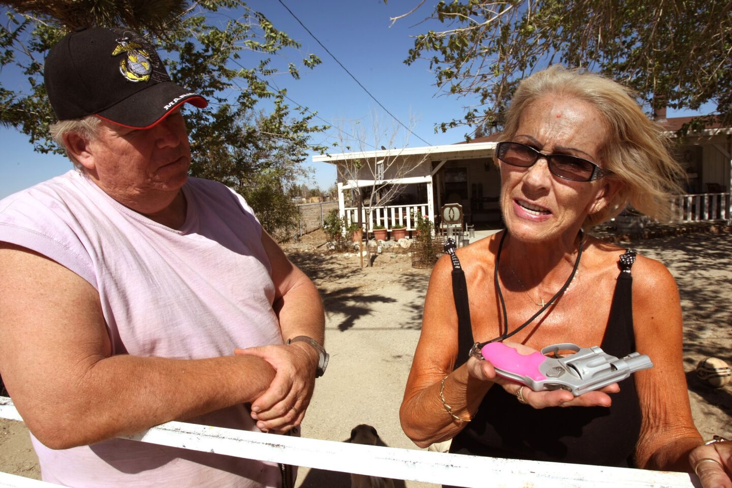 Jane Hammer, shown with her husband Rally, holds the pistol she carries around her neck when walking near her home. The Hammers live down the road from where Pamela Devitt was killed by a pack of dogs on May 9.