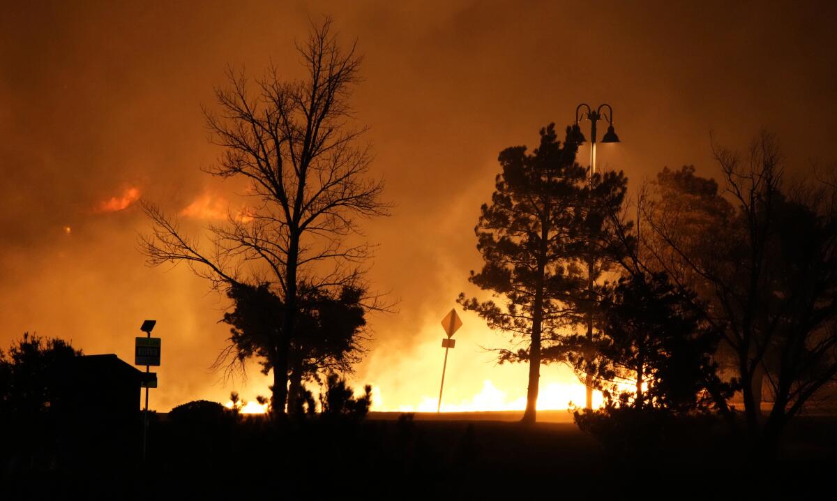 Las llamas arden mientras los incendios forestales crecen cerca de un pequeño centro comercial