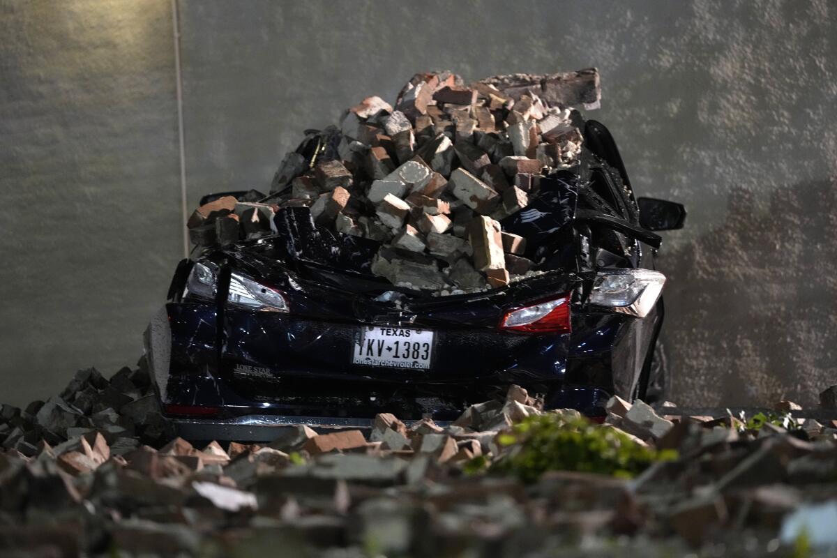 A crushed car is covered by bricks.