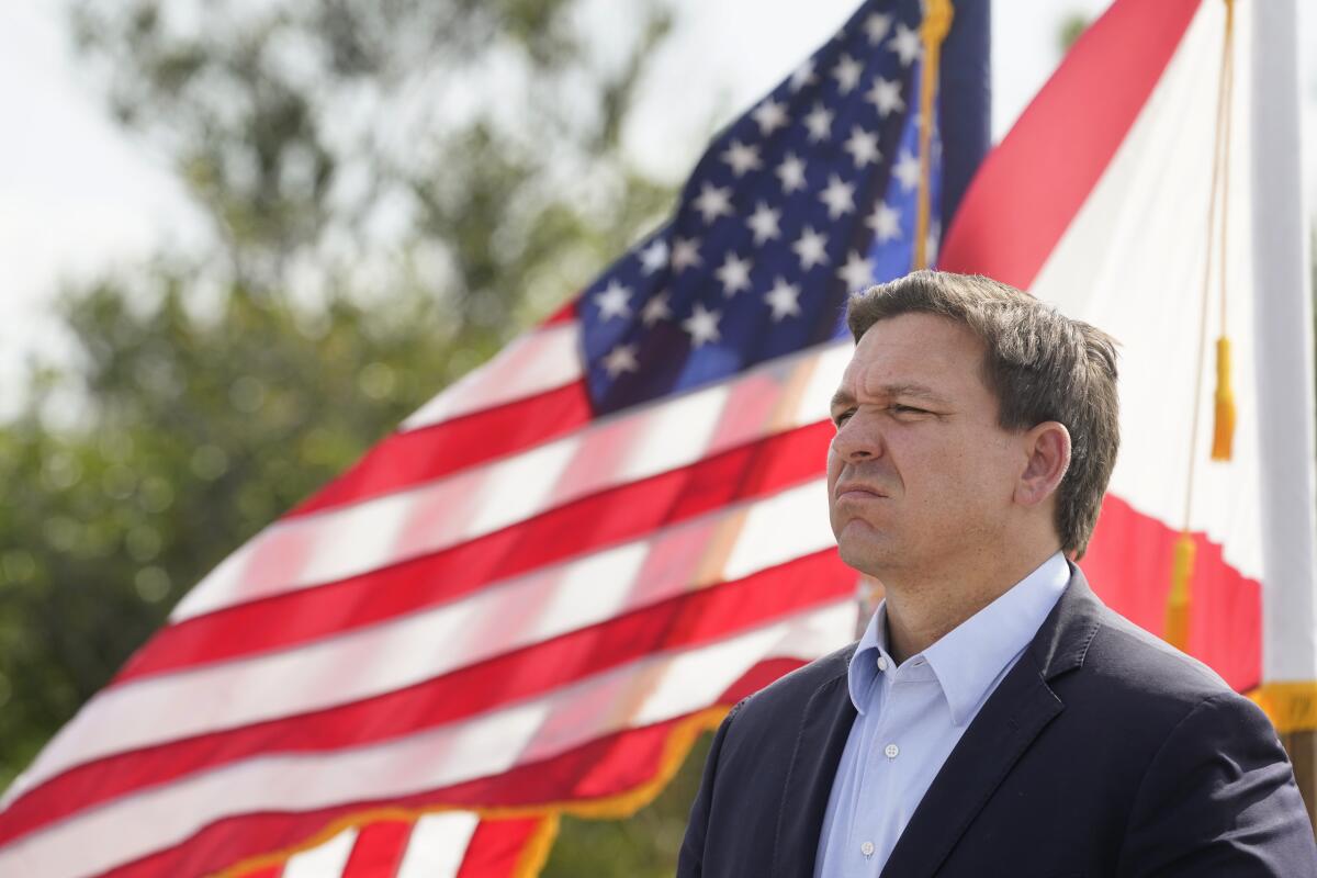 A man appears before an American flag.