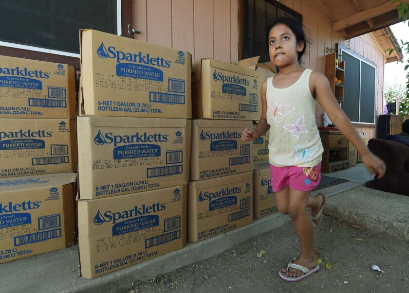 An 8-year-old girl runs past boxes of bottled water supplied by local authorities in the drought affected town of Monson, Calif. In the poorer areas of Tulare County, many homes have run out of water.